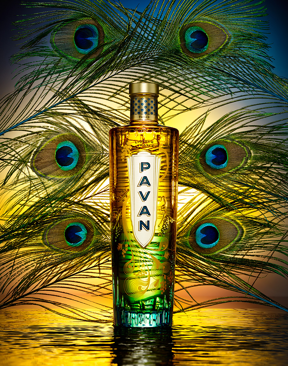 FRENCH LIQUOR PAVAN BOTTLE ON A SUNSET COLORED BACKGROUND WITH PEACOCK FEATHERS SHOT BY DAVID FILIBERTI