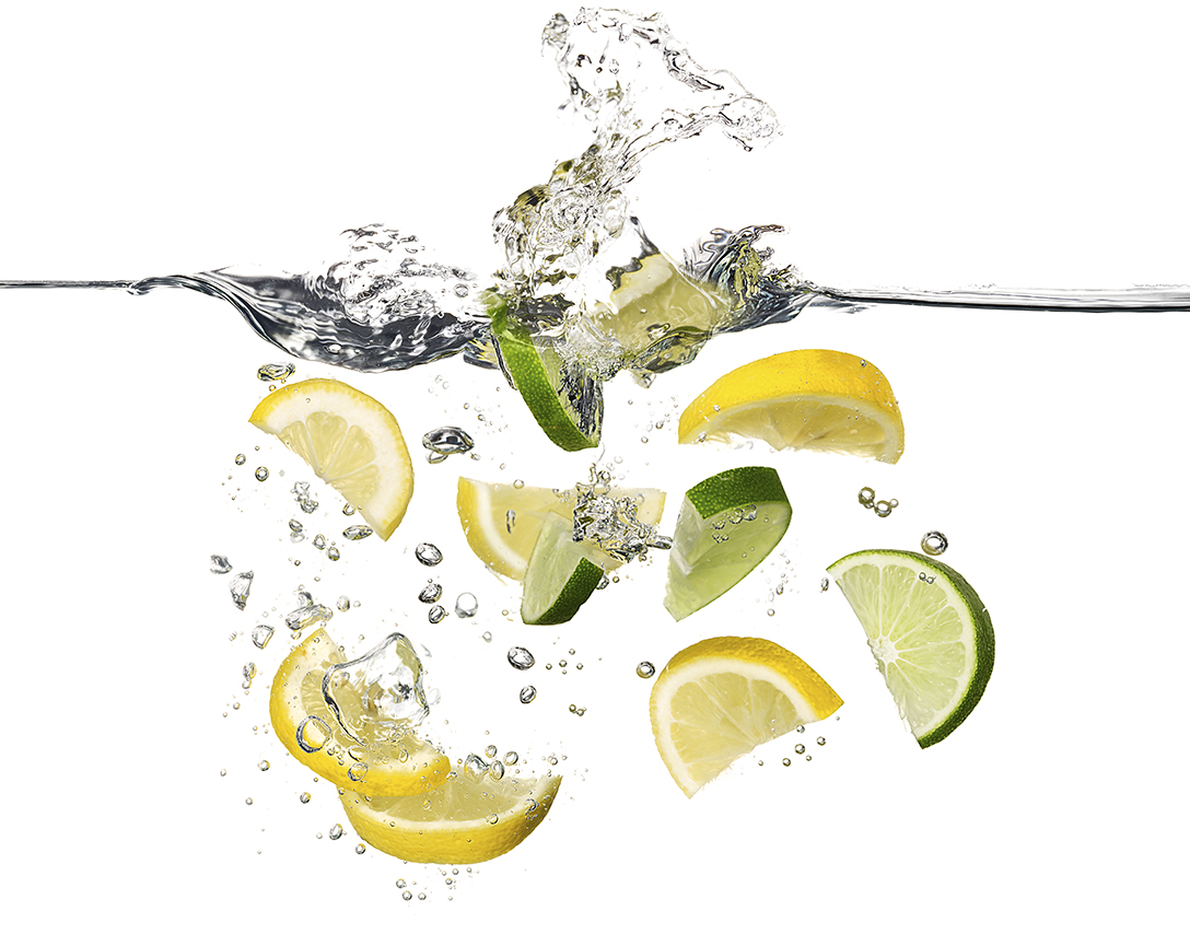 LEMON AND LIME WEDGES SPLASHING INTO WATER SHOT BY DAVID FILIBERTI