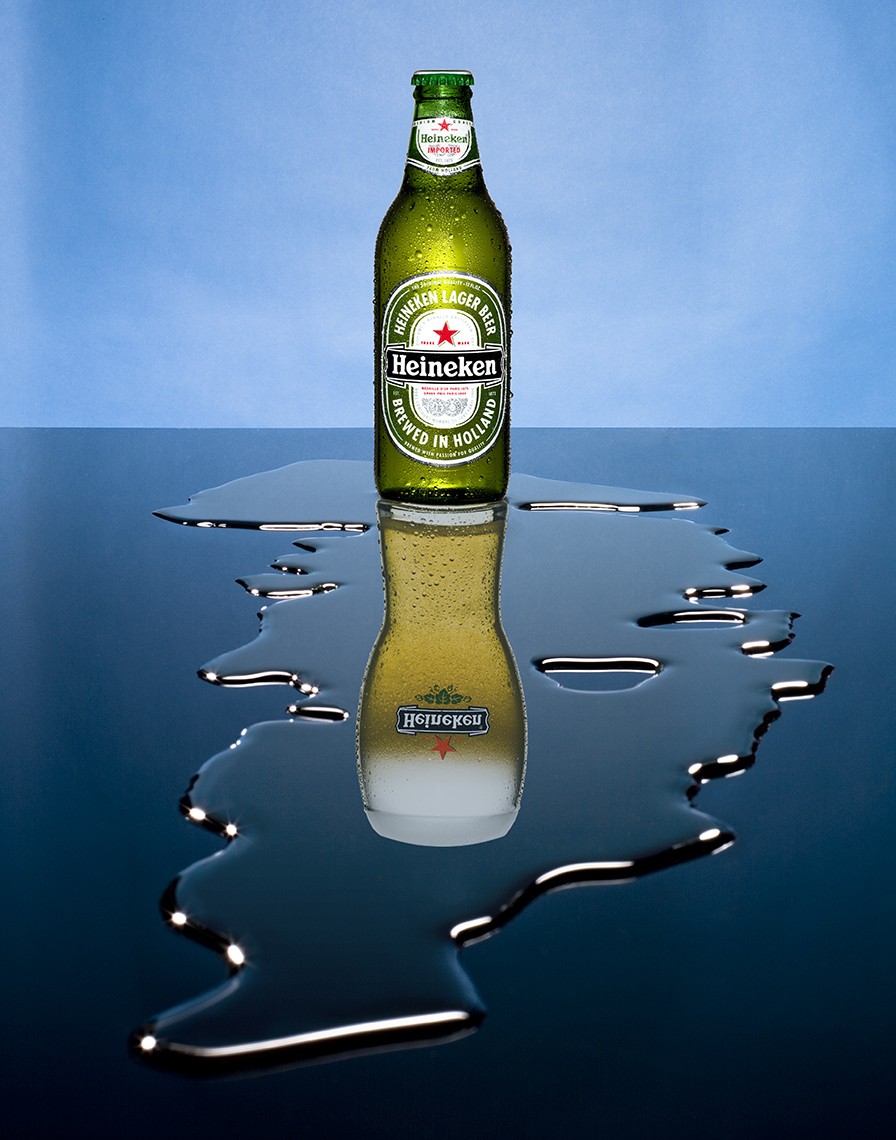 BEER BOTTLE WITH A BEER MUG REFLECTION AND A SPILL OF WATER SHOT BY DAVID FILIBERTI
